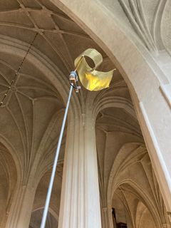 Guldfärgad plåt i toppen av en metallstång, under valven i Västerås domkyrka