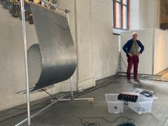 Hängande plåtskiva och sladdar i Västerås domkyrka. Musikern Torbjörn Grass står i bakgrunden.