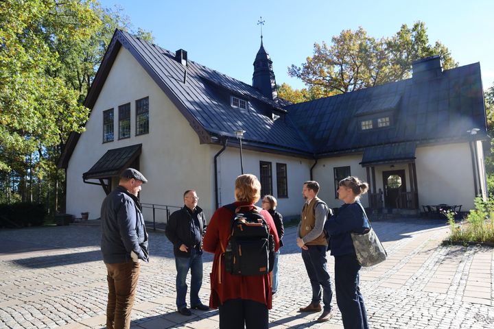 En grupp människor står utanför Viksängskyrkan i höstsolen.