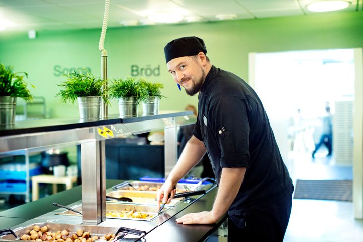 Kökschef som serverar mat i en skolrestaurang.