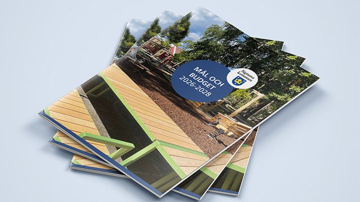 Alt text: Flera exemplar av broschyren "Mål och budget 2026–2028" på ett bord.