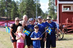 Gruppbild med sju personer utomhus som håller svenska flaggor.