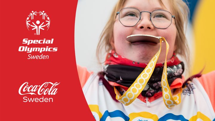 Bilden är ett montage. Till vänster syns logotyperna för Special Olympics Sverige och Coca-Cola Sverige mot en röd bakgrund. Till höger syns en närbild på en tjej med downs syndrom som biter i en medalj.