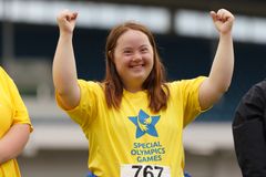 Idrottare med gulblå t-shirt med Special Olympics-logga som sträcker händerna i luften.