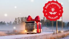 En buss dekorerad som en julklapp kör på en dimmig landsväg. En röd etikett med texten "Årets smartaste julklapp 2025" syns i hörnet.