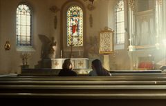 En ung kvinna sitter tillsammans med en präst i kyrkan.