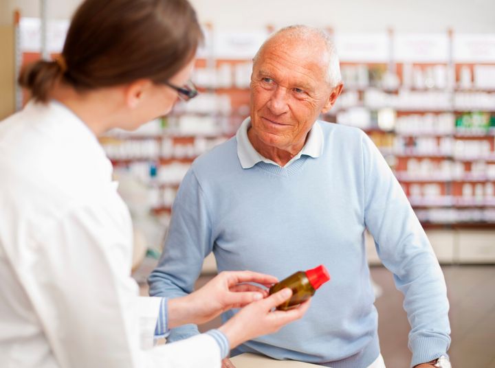 Äldre man får läkemedelsrådgivning på apotek