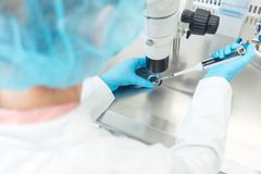 Person i laboratoriemiljö använder mikroskop och pipett.