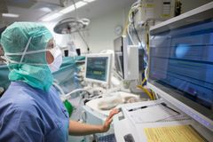 En vårdpersonal i skyddskläder använder en dator för att hantera digitala hälsojournaler i ett sjukhus.