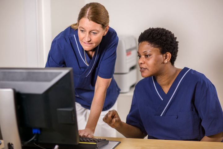 Sjukvårdspersonal diskuterar vid dator