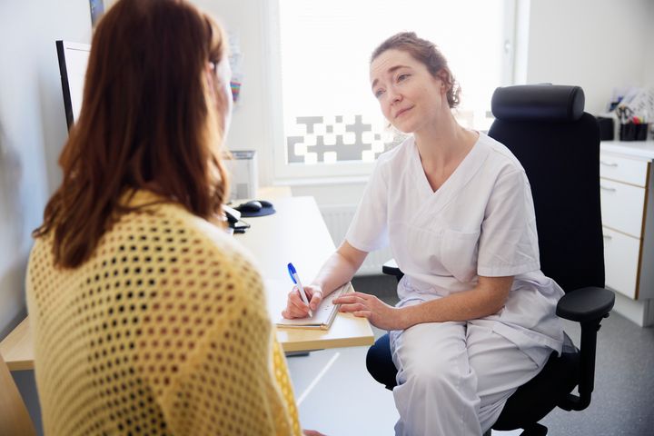 En vårdgivare i samtal med en patient på ett kontor.