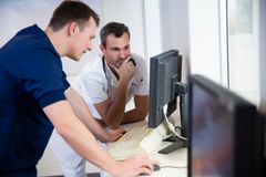 Två män i arbetskläder tittar på en datorskärm och diskuterar.