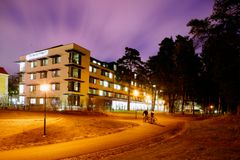 Byggnad i kvällsljus med cyklister på en gångväg framför.