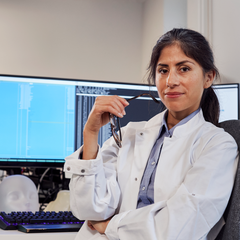 Kvinna i vit rock framför datorskärmar