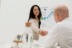 Kvinna skakar hand med en man i ett konferensrum.