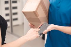 Hand som signerar mottagande av leverans på en mobiltelefon och ett paket som ska lämnas över