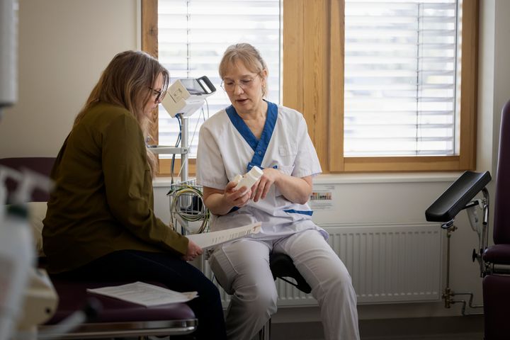 En sjuksköterska diskuterar medicinsk information med en patient på en vårdcentral.