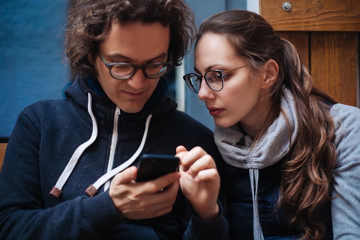 Två personer tittar tillsammans på information i en mobiltelefon.
