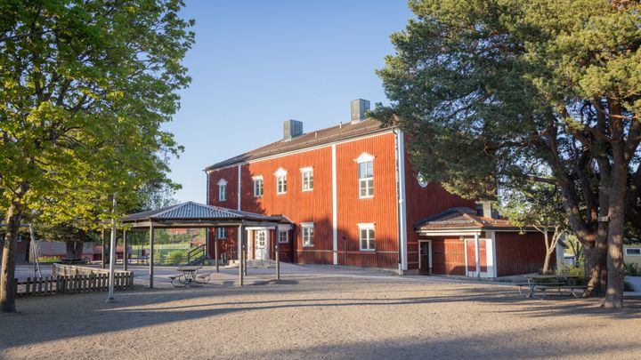En bild på en röd skolbyggnad.