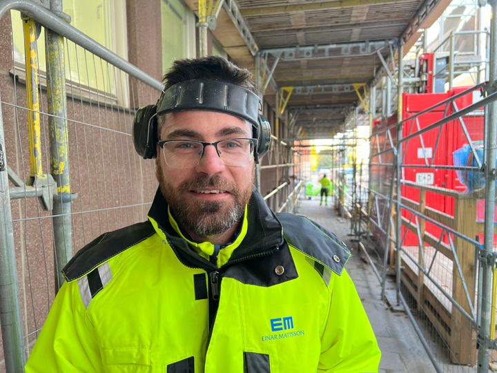 Snickaren Gabor Szanto står utomhus i en gång under byggställningar. Han är glad över utmärkelsen som Årets skyddsombud i Stockholm.