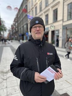 En person står på en stadsgata och håller ett flygblad.