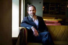 En person i kostym sitter på en soffa i ett upplyst rum.