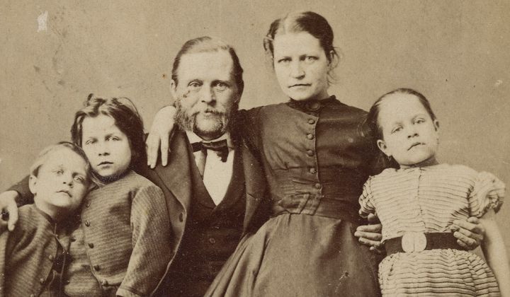 En okänd familj med tre barn. Porträttet skiljer sig från samtidens väl arrangerade familjebilder. Kläder och visitkort tyder på mitten av 1860-talet. Fotograf: okänd