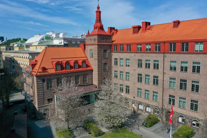 Beige fastighet med rött tak i solen med blå himmel i bakgrunden