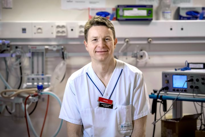 En person i vit sjukhusklädsel står i ett rum med medicinsk utrustning.