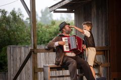 En scen från en teaterföreställning med en man som spelar dragspel och ett barn som nyper honom i näsan.