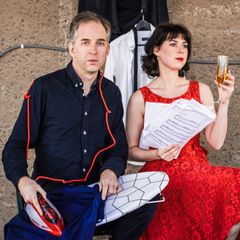 En man och en kvinna poserar. Mannen håller ett strykjärn och kvinnan ett glas.