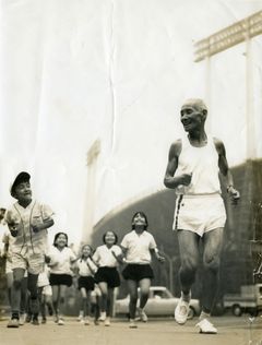 Shiso Kanakuri springer tillsammans med skolbarn utanför Olympiastadion inför invigningen av de olympiska spelen i Tokyo 1964.