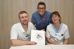 Tre sjukvårdspersonal sitter och ler mot kameran. De håller en pärm med texten Hornhinnedonation.