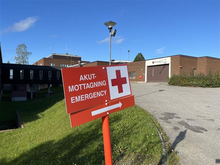 Skylt som visar vägen till akutmottagningen i Kalix, med ett kors och texten "Emergency".