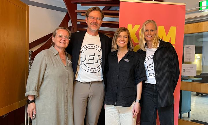 Fyra personer står tillsammans vid en workshop med en skylt i bakgrunden.