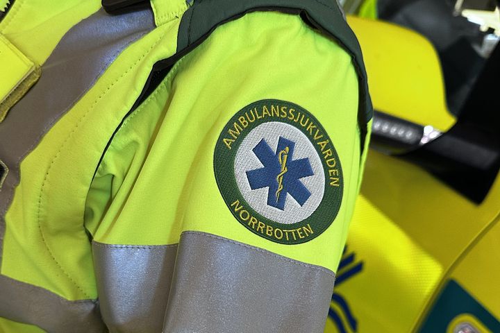 Person i ambulansuniform med texten "Ambulanssjukvården Norrbotten" på ärmen.