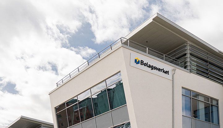 Vit byggnad med Bolagsverkets logotyp på fasaden under en molnig himmel.