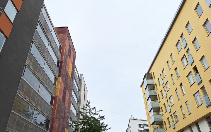 Flerbostadshus till vänster och höger om en gråblå himmel