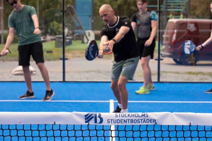 En grupp människor spelar padel på en utomhusbana.