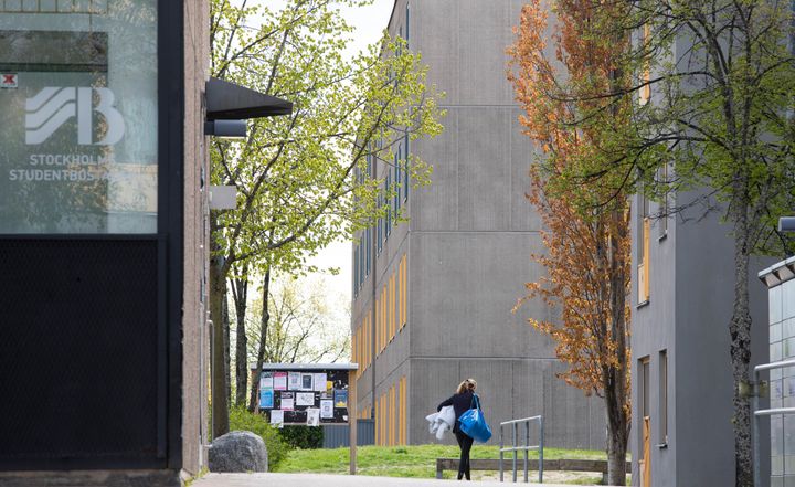 En person går med en påse mellan byggnader på Kungshamra studentbostäder i Solna.