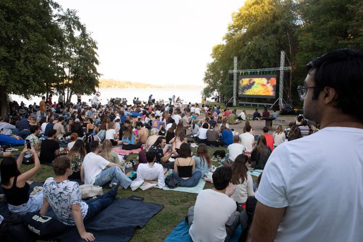 Utomhusbio vid Lappis Beach med en stor publik som tittar på en film på en stor skärm.