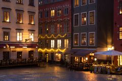 Kvällsbild av upplysta byggnader och restaurang i Gamla stan.