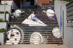 En student sitter framför en målning av en trappa, dekorerad med rymdmotiv.