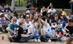 En grupp studenter sitter tillsammans på Lappis Beach för en utomhusbio.