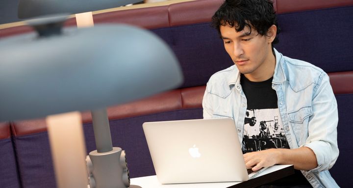 En person sitter vid en bärbar dator och studerar.