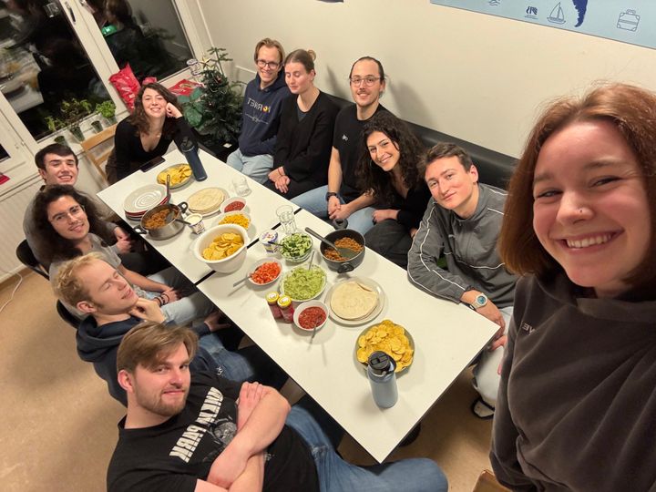 Grupp studenter sitter runt ett bord med tacos och tillbehör.