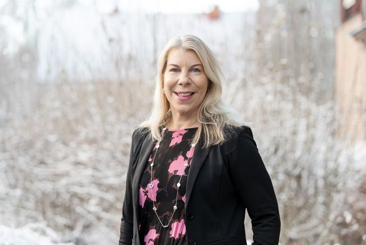 Anette Madsen porträtterad framför lätt snötäckta träd och buskar.