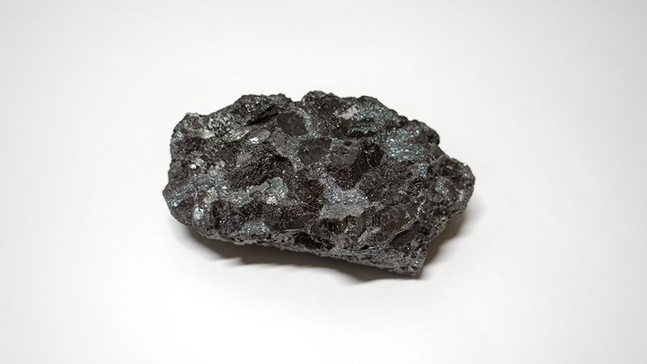 Bild på prov av magnetitmalm mot vit bakgrund.