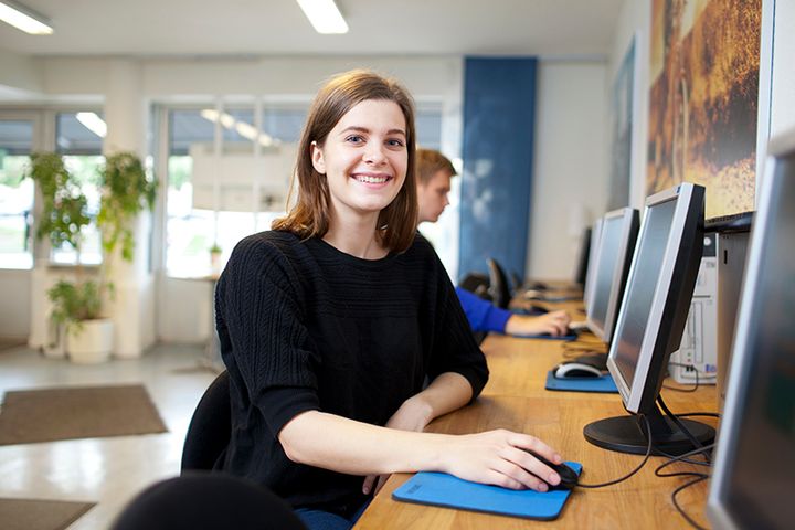 Kvinna sitter framför dataskärm.