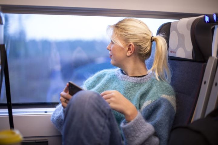 Kvinna sitter på tåg och tittar ut genom fönsterrutan.